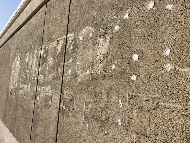 Close-up of sign ghosting and patch marks on stucco fascia